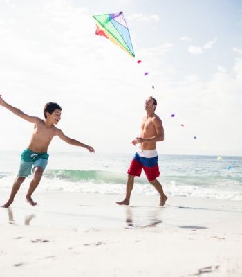 Vater und Sohn beim Drachensteigen am Strand der Nordsee